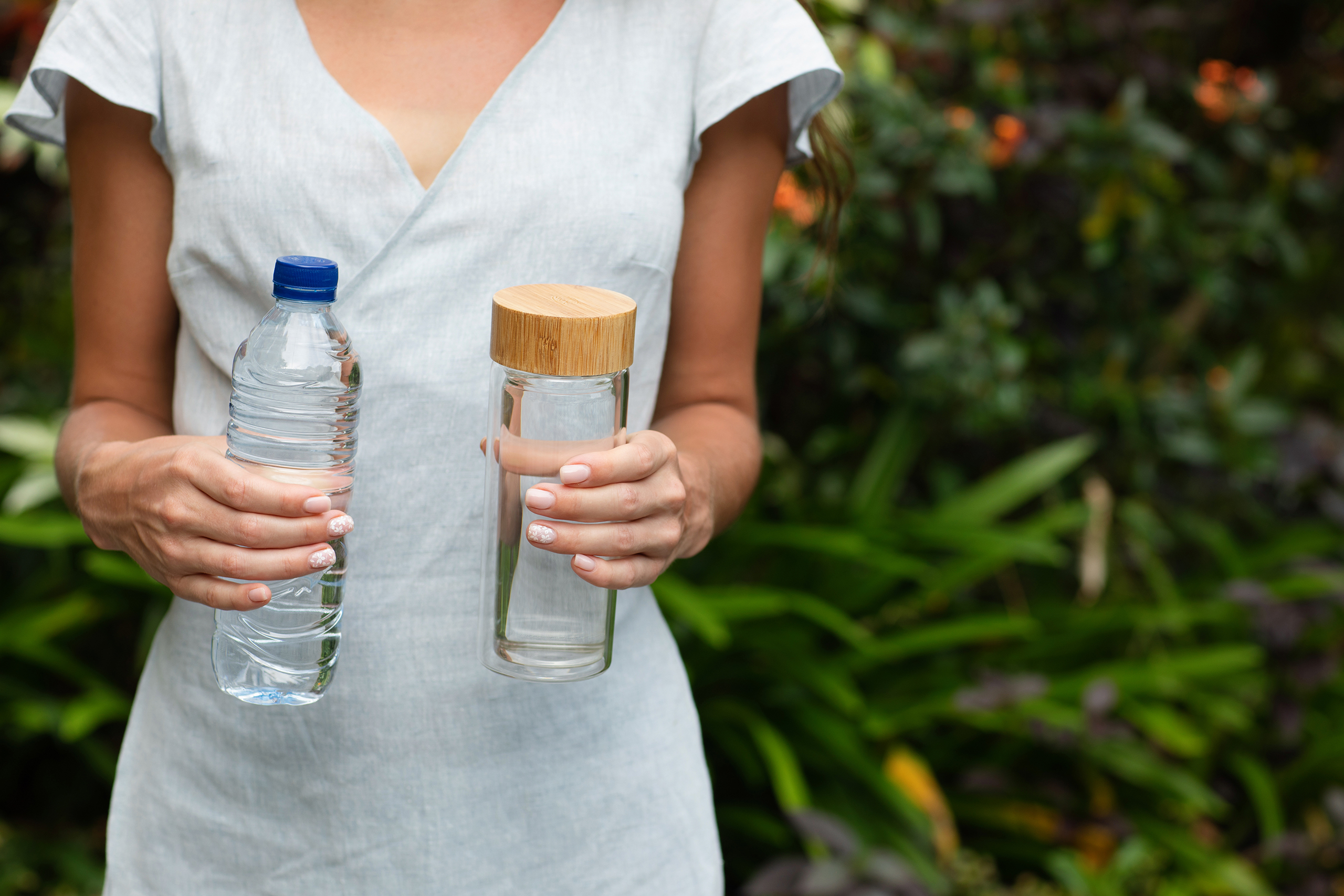 A recent study found that plastics may be more sustainable than some other materials in terms of the life cycle of the materials. This is an image of a woman holding a plastic bottle and a glass bottle.