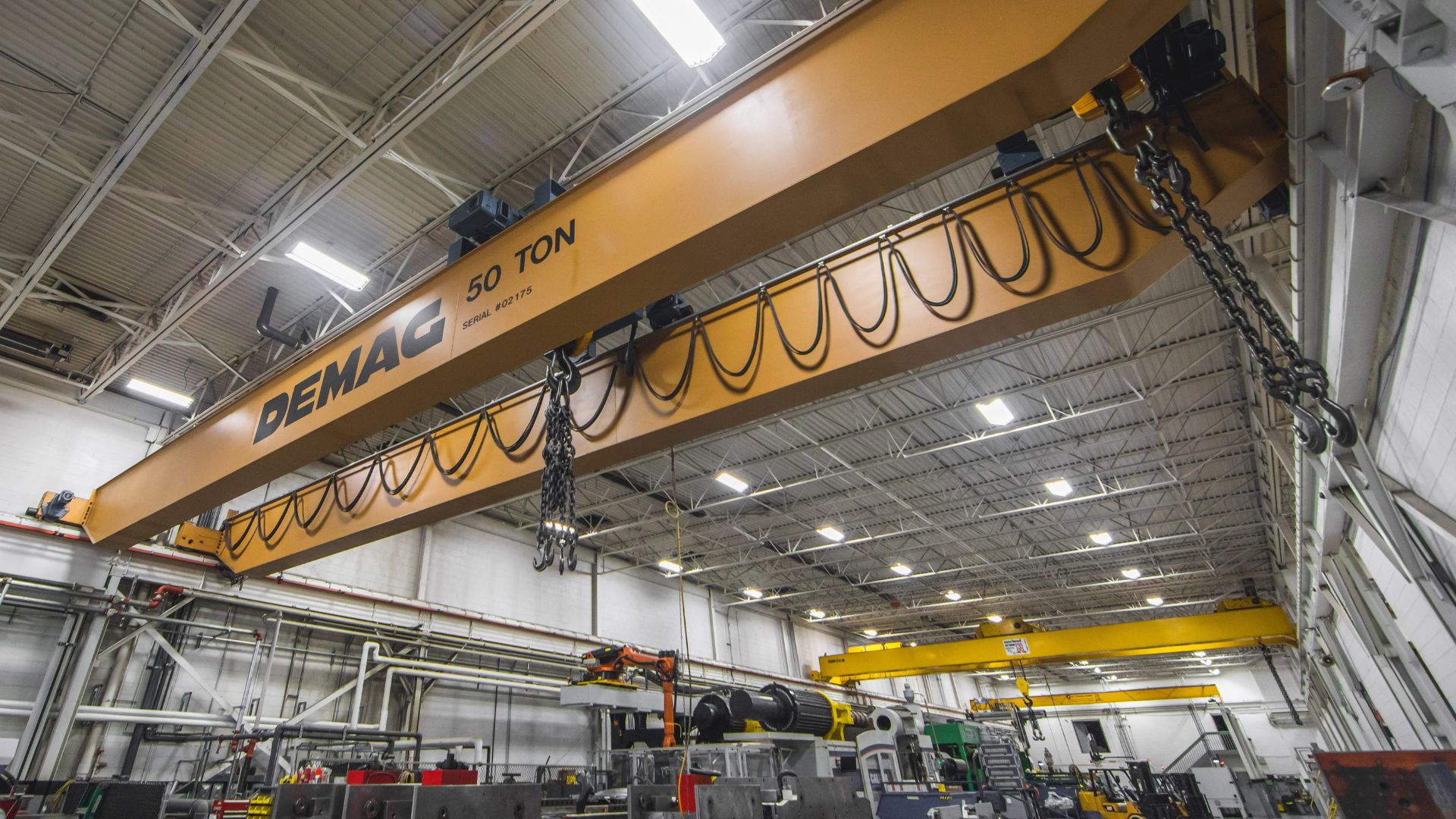 Plastic Molding Development warehouse featuring a large yellow overhead crane labeled "DEMAG 50 TON" used for lifting heavy materials.